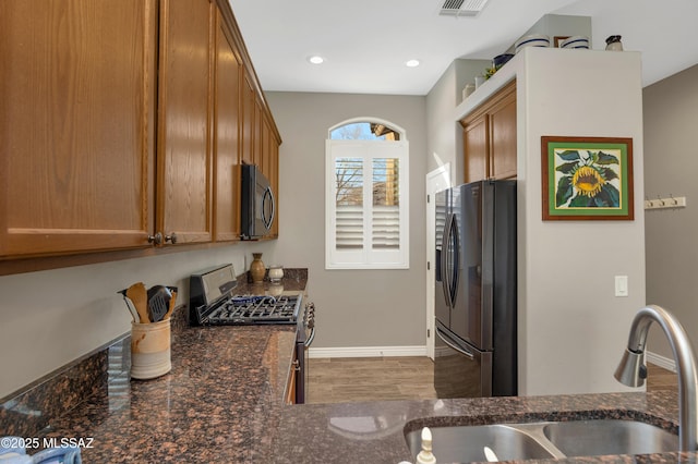 kitchen featuring sink, stainless steel appliances, and dark stone countertops