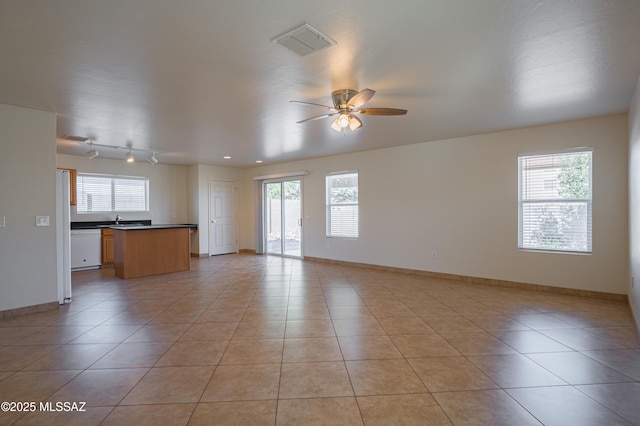 tiled empty room featuring ceiling fan and plenty of natural light