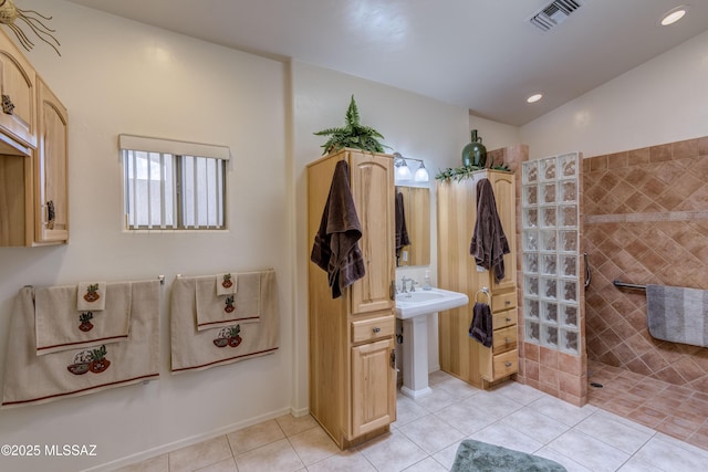 bathroom featuring sink, tiled shower, tile patterned flooring, and vaulted ceiling