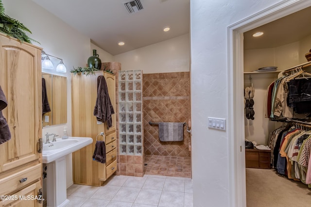 bathroom with a shower, vaulted ceiling, and tile patterned floors