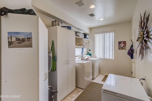 clothes washing area with washing machine and dryer and light tile patterned floors