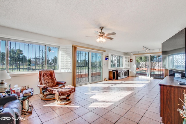 interior space featuring ceiling fan, light tile patterned floors, and a textured ceiling