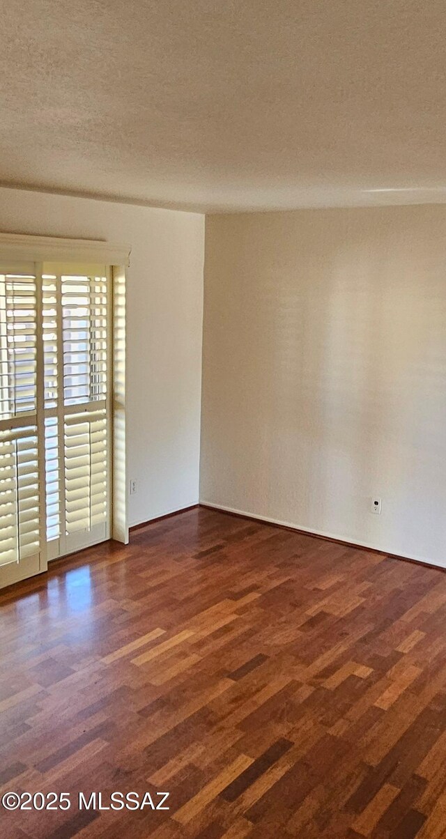 spare room featuring a textured ceiling and dark wood-type flooring