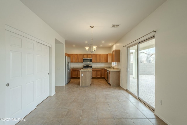 kitchen with appliances with stainless steel finishes, sink, hanging light fixtures, a center island, and an inviting chandelier