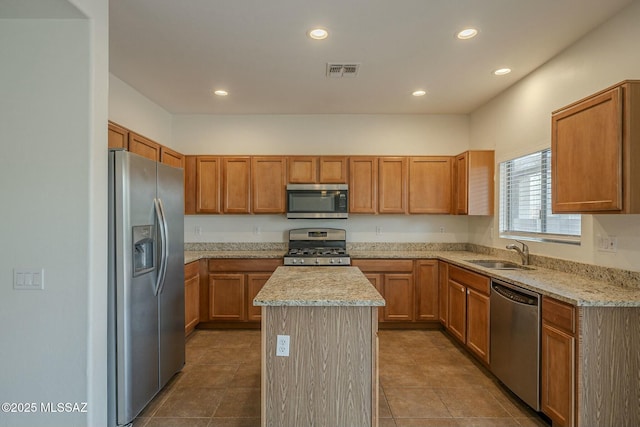 kitchen featuring sink, a kitchen island, light stone countertops, and appliances with stainless steel finishes