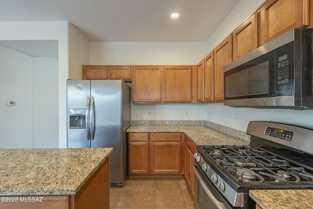 kitchen featuring light stone countertops, stainless steel appliances, and light tile patterned flooring