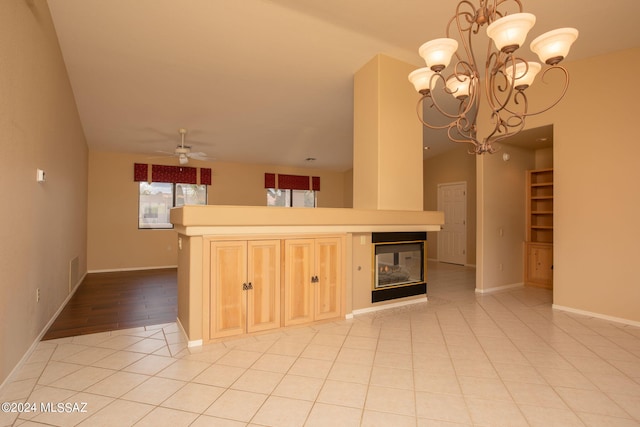 kitchen featuring pendant lighting, light brown cabinets, ceiling fan with notable chandelier, a multi sided fireplace, and light tile patterned flooring