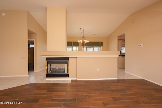 unfurnished living room featuring vaulted ceiling, a multi sided fireplace, and a chandelier