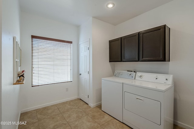 clothes washing area featuring cabinets, light tile patterned floors, a healthy amount of sunlight, and washing machine and clothes dryer