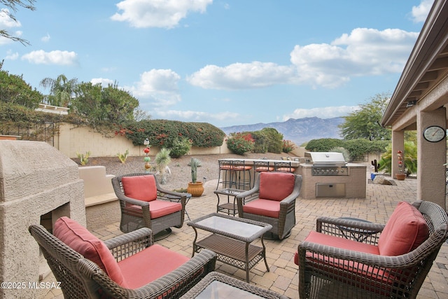 view of patio / terrace featuring a mountain view, an outdoor kitchen, an outdoor hangout area, and a grill