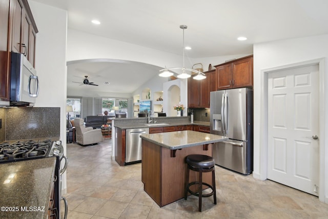 kitchen featuring kitchen peninsula, vaulted ceiling, decorative light fixtures, backsplash, and stainless steel appliances