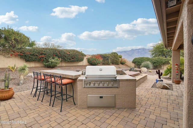 view of patio / terrace featuring exterior kitchen, grilling area, a bar, and a mountain view