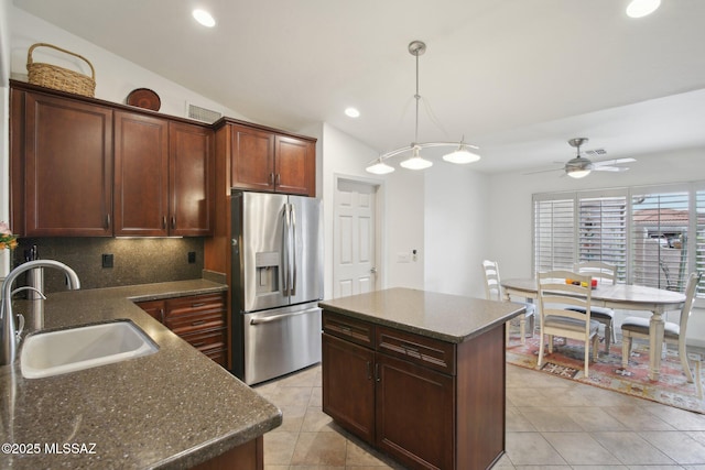 kitchen with a center island, tasteful backsplash, stainless steel refrigerator with ice dispenser, sink, and lofted ceiling