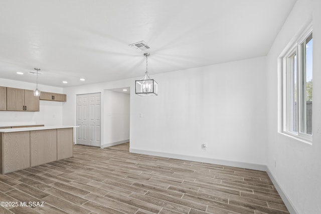 interior space with a notable chandelier, decorative light fixtures, light wood-type flooring, and a wealth of natural light