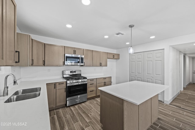 kitchen featuring appliances with stainless steel finishes, decorative light fixtures, a kitchen island, and sink