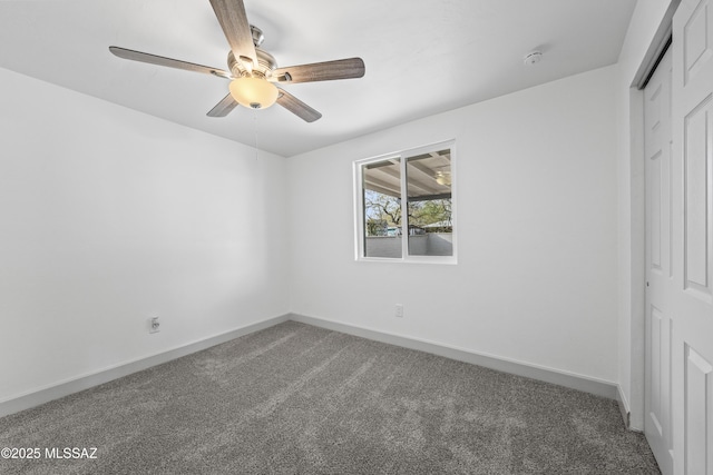 unfurnished bedroom with a closet, dark carpet, and ceiling fan