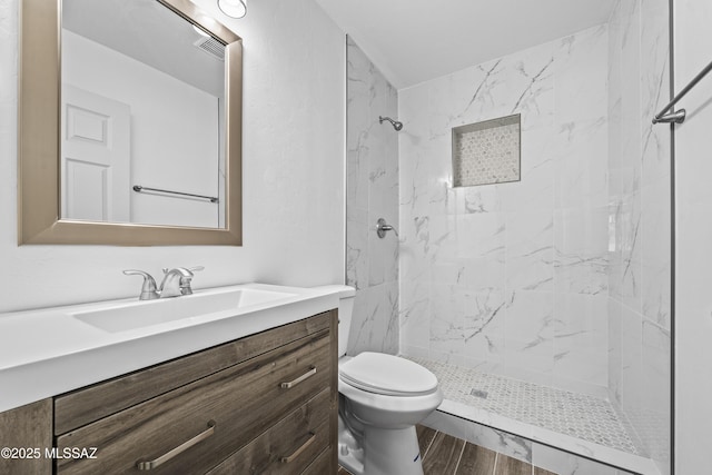 bathroom featuring vanity, toilet, and tiled shower