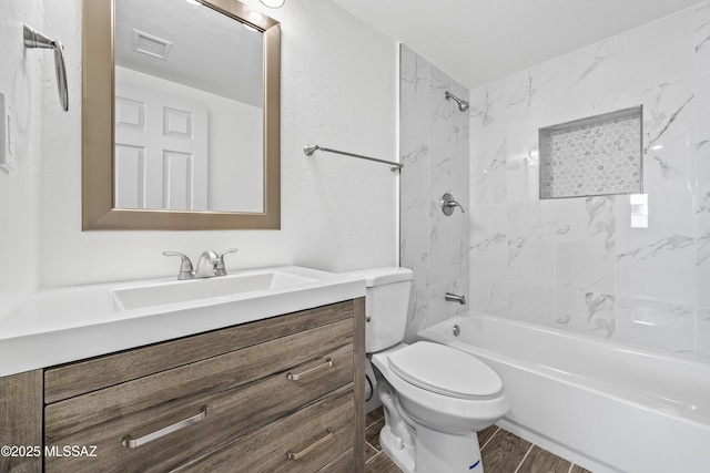 full bathroom featuring vanity, tiled shower / bath, and toilet