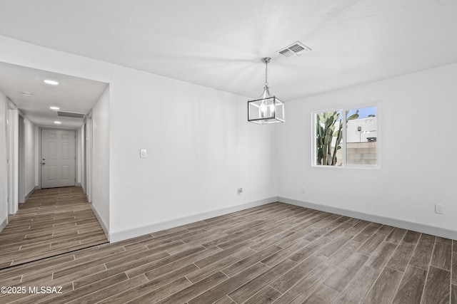 unfurnished room featuring dark hardwood / wood-style flooring and an inviting chandelier