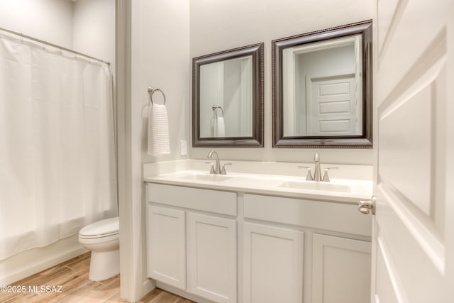 full bathroom with hardwood / wood-style floors, vanity, toilet, and shower / bath combo