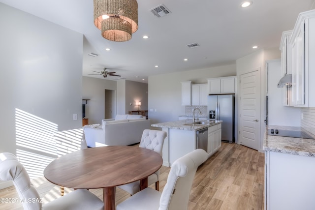 kitchen with backsplash, light stone countertops, white cabinets, and appliances with stainless steel finishes