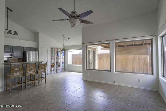 unfurnished room featuring ceiling fan, light tile patterned floors, vaulted ceiling, and a textured ceiling