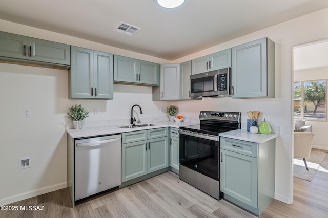 kitchen with sink, appliances with stainless steel finishes, and light hardwood / wood-style flooring