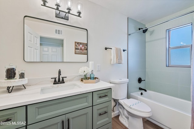 full bathroom featuring vanity, hardwood / wood-style flooring, toilet, and tiled shower / bath