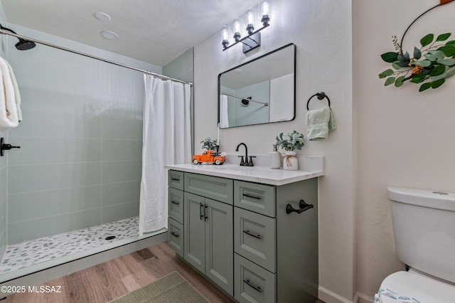 bathroom with hardwood / wood-style floors, vanity, toilet, and walk in shower