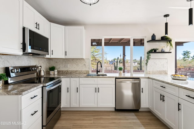 kitchen featuring light stone countertops, white cabinetry, sink, hanging light fixtures, and stainless steel appliances