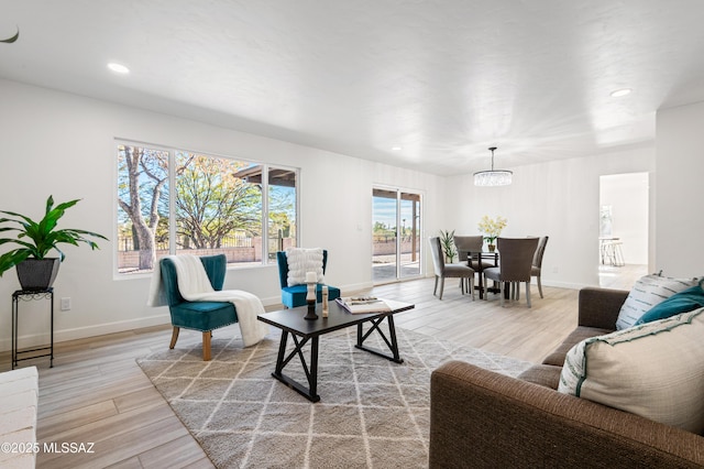 living room with light wood-type flooring and an inviting chandelier