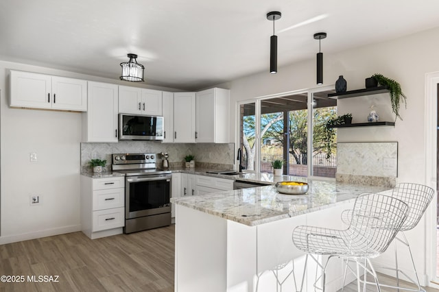 kitchen featuring kitchen peninsula, white cabinetry, and stainless steel appliances