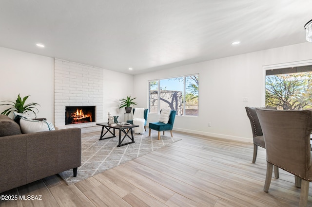 living room with light wood-type flooring and a brick fireplace