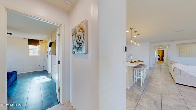 hall featuring sink and light tile patterned flooring