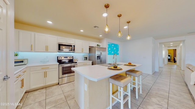 kitchen with stainless steel appliances, sink, light tile patterned floors, decorative light fixtures, and white cabinetry