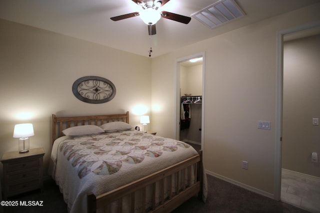 bedroom featuring ceiling fan, dark carpet, a walk in closet, and a closet