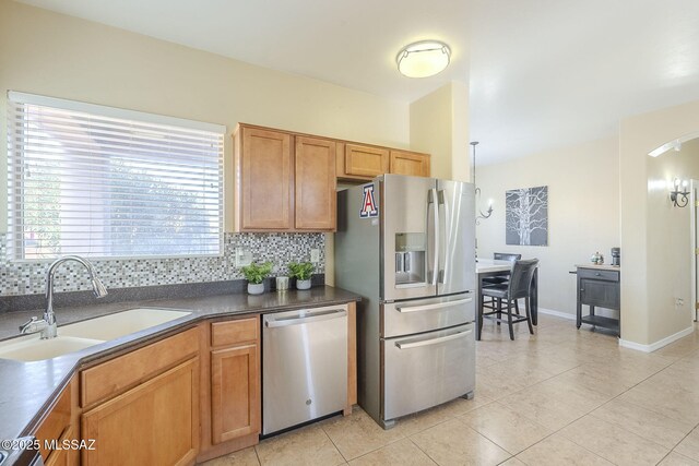 kitchen with backsplash, sink, light tile patterned flooring, and appliances with stainless steel finishes