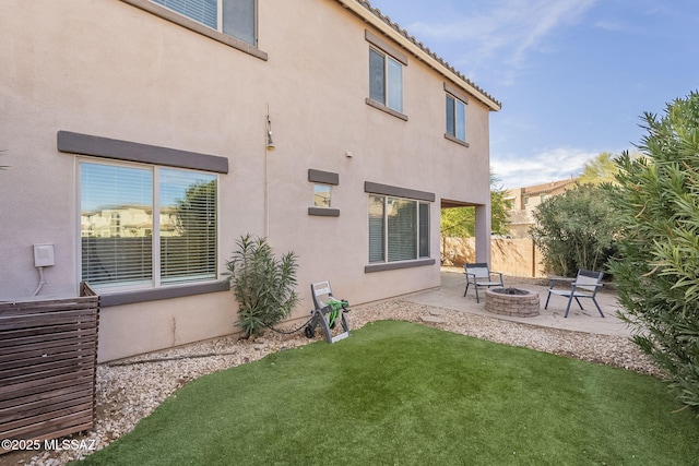 rear view of property featuring a patio area, a yard, and an outdoor fire pit