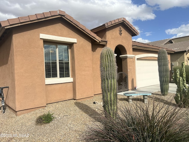 exterior space with a tiled roof, an attached garage, and stucco siding