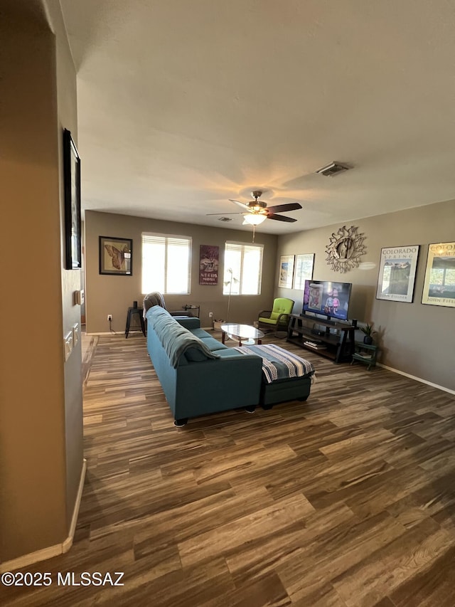 living room featuring dark wood-type flooring, a ceiling fan, visible vents, and baseboards