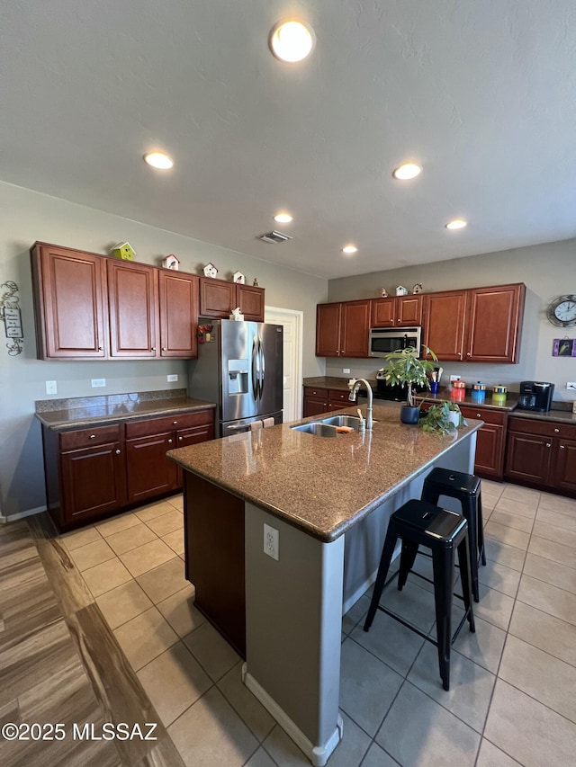 kitchen with a breakfast bar area, recessed lighting, a kitchen island with sink, a sink, and stainless steel appliances