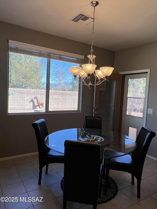 tiled dining room featuring a chandelier, visible vents, and baseboards