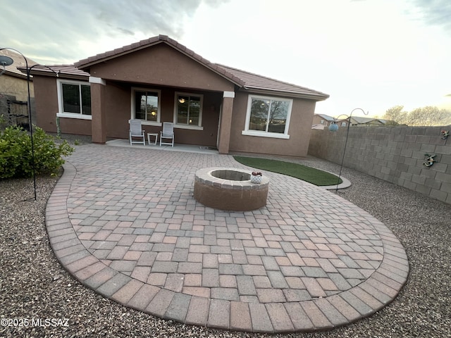 rear view of property featuring a patio, stucco siding, a fire pit, a tiled roof, and fence private yard