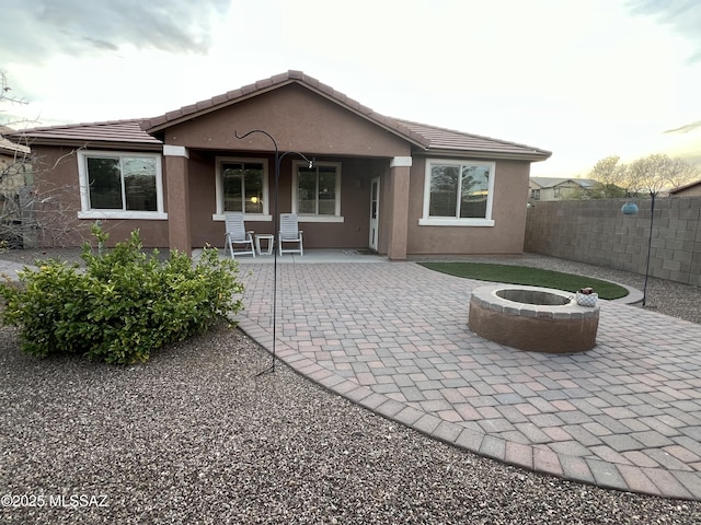 rear view of property with a patio area, stucco siding, a fire pit, and fence