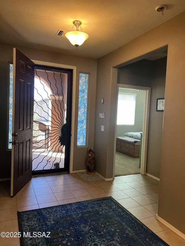 foyer with visible vents, baseboards, and light tile patterned flooring