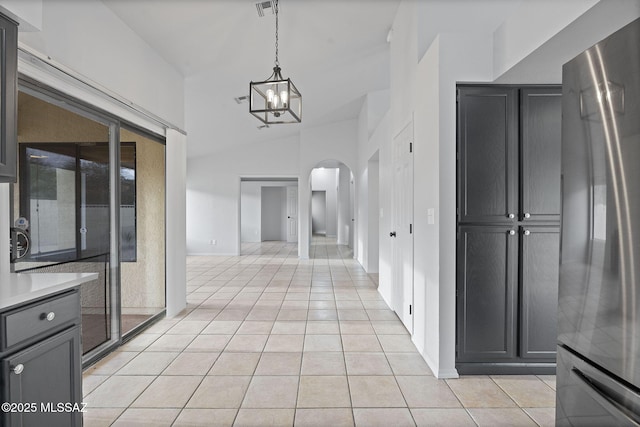 corridor featuring a notable chandelier, light tile patterned floors, and vaulted ceiling