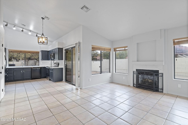 unfurnished living room featuring vaulted ceiling, sink, light tile patterned floors, a notable chandelier, and a fireplace