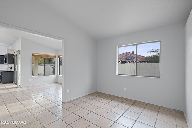 tiled empty room featuring vaulted ceiling