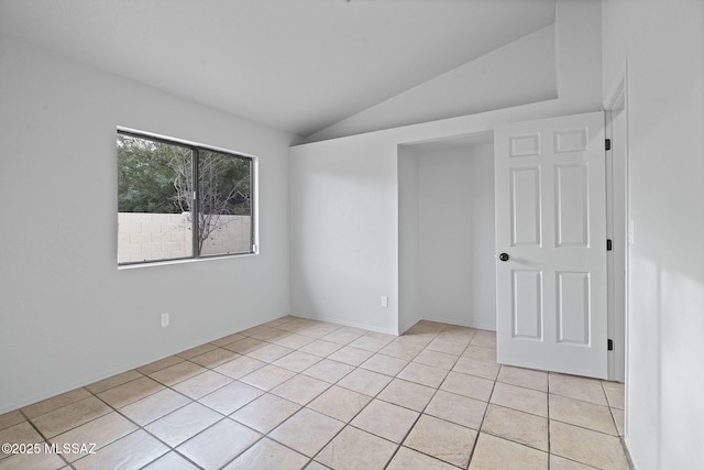 spare room featuring light tile patterned floors and vaulted ceiling