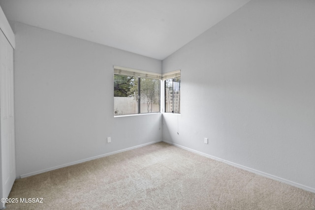 carpeted empty room featuring vaulted ceiling